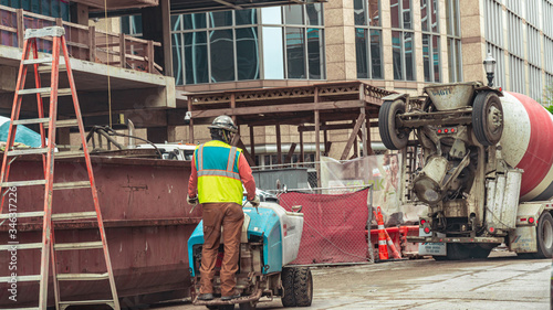 Construction workers and cement trucks working on a highrise in the city