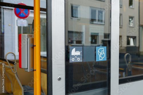 Selected focus at face mask covering mouth and nose symbol on blue sign on glass of public transportation's window door in Germany during epidemic of COVID-19 virus and German face mask regulations.