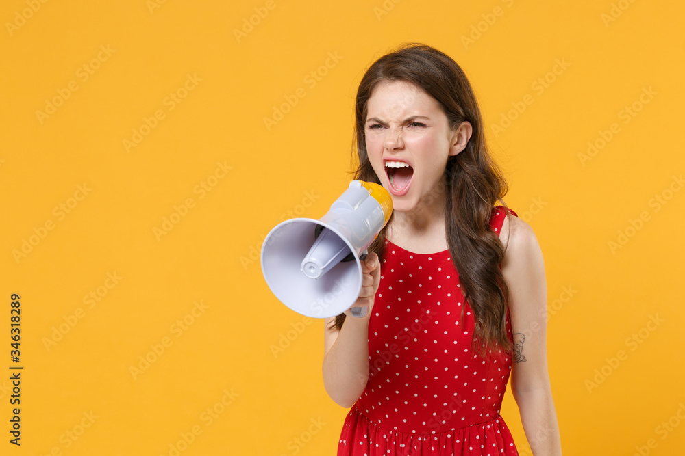 Irritated young brunette woman girl in red summer dress posing isolated on yellow wall background studio portrait. People sincere emotions lifestyle concept. Mock up copy space. Scream in megaphone. Irritated young brunette woman girl in red summer dress posing isolated on yellow wall background studio portrait. People sincere emotions lifestyle concept. Mock up copy space. Scream in megaphone.