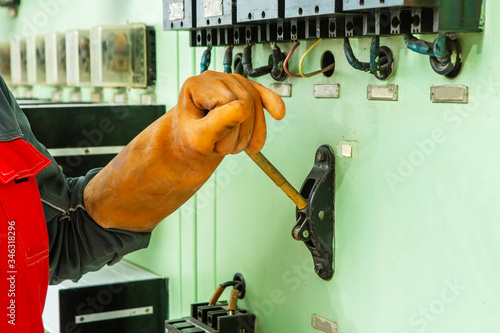 The worker in a rubber glove turns on the switch