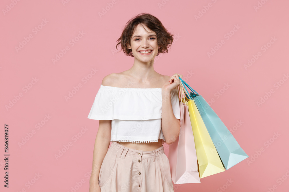 Smiling young woman girl in summer clothes hold package bag with purchases isolated on pastel pink wall background studio portrait. Shopping discount sale concept. Mock up copy space. Looking camera.