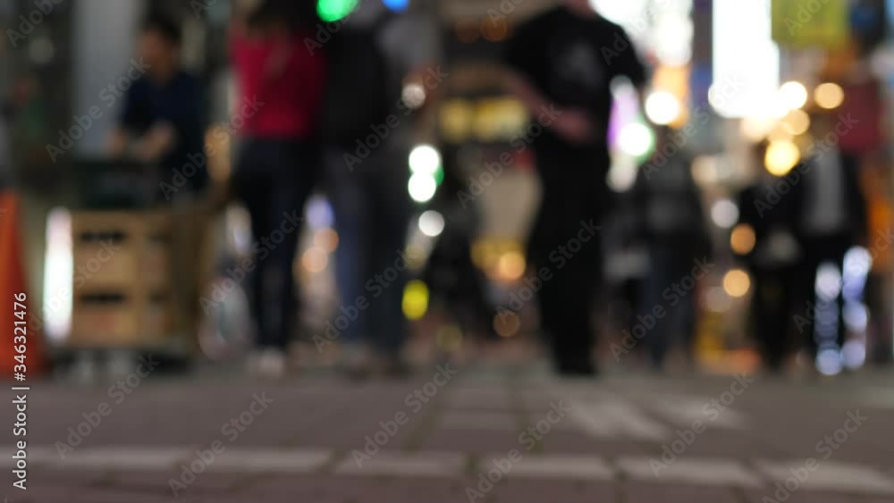 Blurred silhouettes of people at pedestrian alley, Ueno area in night time. Popular place for dinning and entertainment. Tokyo nightlife concept. Bright signs on background, low camera position Blurred silhouettes of people at pedestrian alley, Ueno area in night time. Popular place for dinning and entertainment. Tokyo nightlife concept. Bright signs on background, low camera position