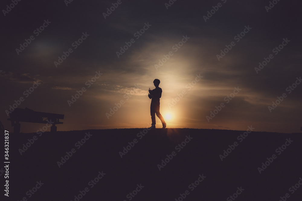 夕暮れの丘に立つ男性のシルエット