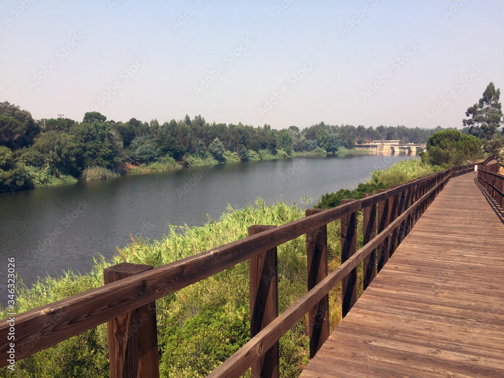 wooden footbridge in perspective on the river bank