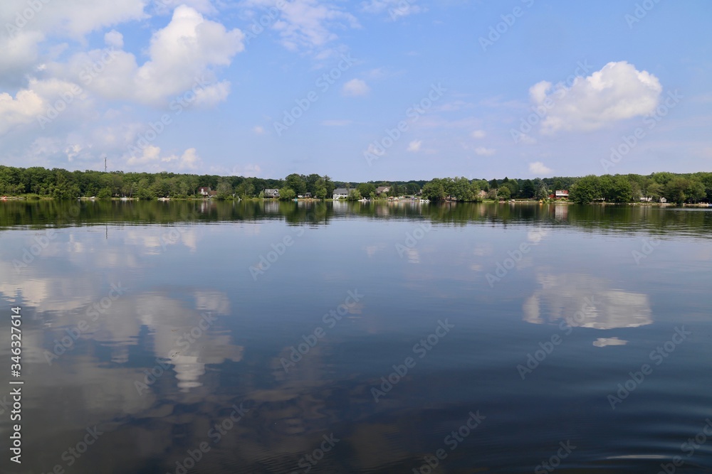 lakefront homes and land and blue sky reflected in a placid lake
