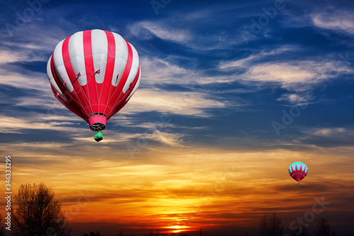 Red and white hot air balloons on the background of bright orange sunset.