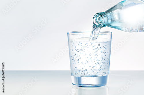 Pouring water from bottle into glass with place for text. Mineral water.
