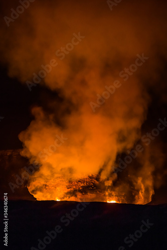 As darkness of night envelopes the crater  smoke and fire rise at Kilauea volcano.