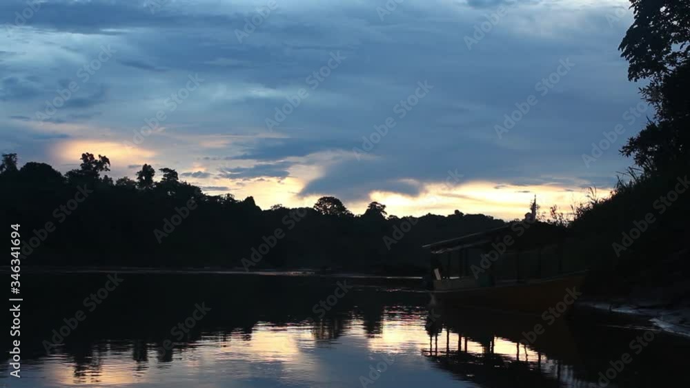 Amazon rainforest sunset on the river with a floating boat. Amazon rainforest sunset on the river with a floating boat.