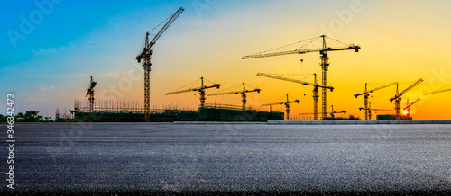 Empty asphalt road and construction site landscape at sunrise.