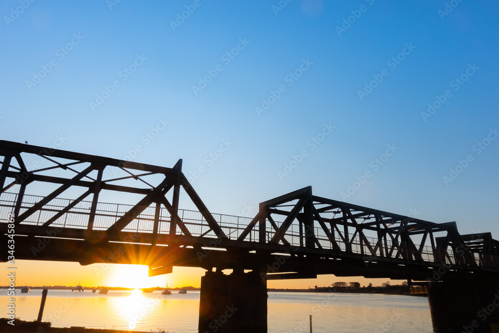 Railway bridge silhouetted by sunrise