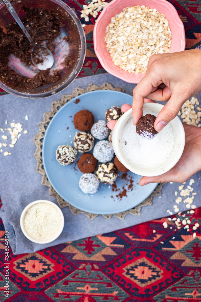 Woman makes chocolate truffle coconut protein vegan balls. Sweet breakfast dessert ingredients on table.