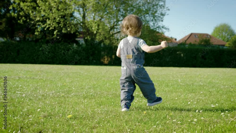 One year old discovering the park with unsteady but sure new steps, warm light