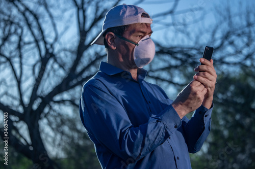 Middle-aged man dressed in blue shirt puzzled by coronavirus situation in parke looking thoughtful