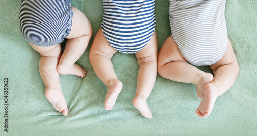Newborn triplets lie on a stomach on a blanket photo