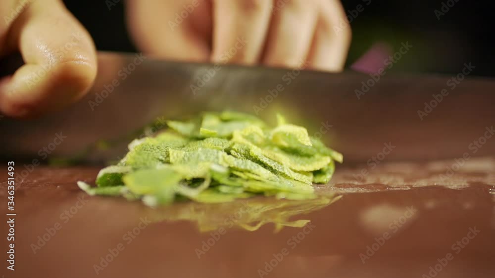the cook cuts green peppers on the cutting board. close up and slow motion.