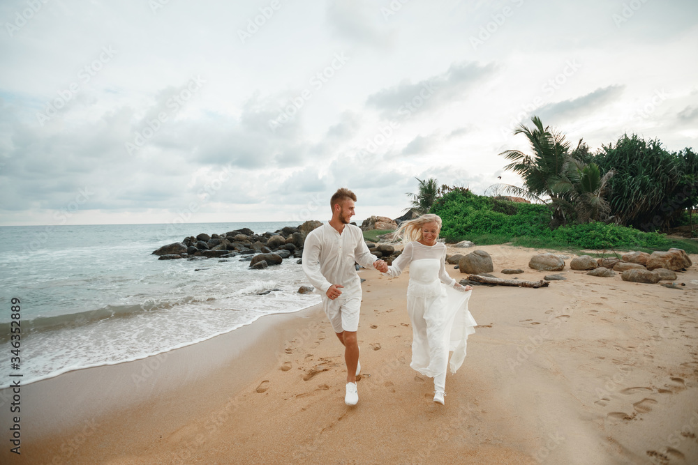 Just married couple running on a sandy beach, smiling and have fun. Tenderness moment of love Just married couple running on a sandy beach, smiling and have fun. Tenderness moment of love