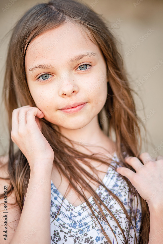 Portrait of a smiling little beautiful girl with long hair. Girl 7-9 years old hands at the face. Portrait of a smiling little beautiful girl with long hair. Girl 7-9 years old hands at the face.
