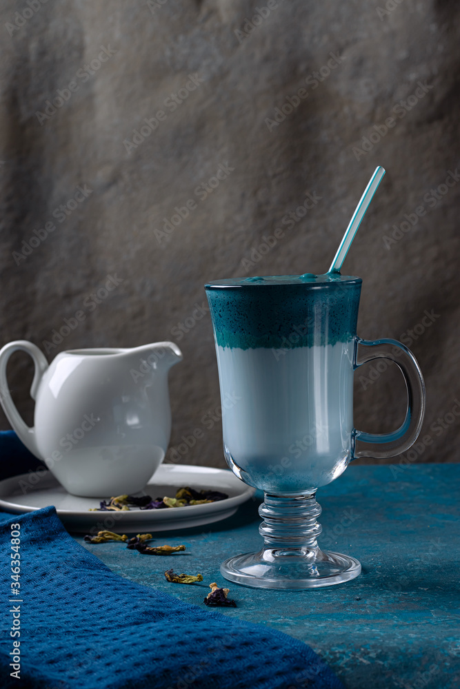 Dalgona Matcha Blue Latte, cream cold drink with milk in a cup on a blue background. Dalgona Matcha Blue Latte, cream cold drink with milk in a cup on a blue background.