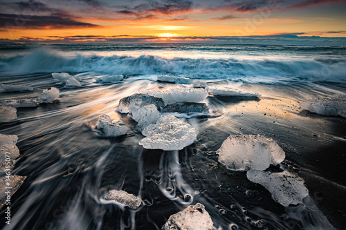 Sun begins to rise over ice chunks at Ice beach at Jokulsarlon photo