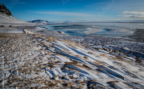 Windswept snow surrounds the partially frozen Jokulsarlon Lagoona photo