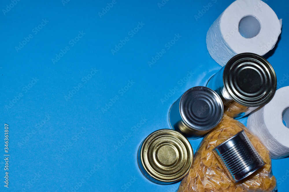 Food delivery on quarantine isolation on a blue background side view. Macaroni, buckwheat, canned food, talet paper. Food delivery on quarantine isolation on a blue background side view. Macaroni, buckwheat, canned food, talet paper.