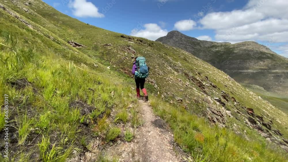Trekking around the bend on a mountain trail, rear view of lone adventure hiker, breathtaking scenery on sunny day with copy space Trekking around the bend on a mountain trail, rear view of lone adventure hiker, breathtaking scenery on sunny day with copy space