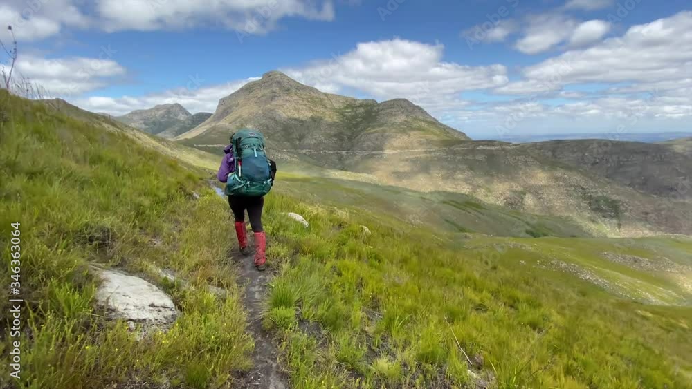 Hike through mountains with backpack, against beautiful cloudy blue sky backdrop day Hike through mountains with backpack, against beautiful cloudy blue sky backdrop day