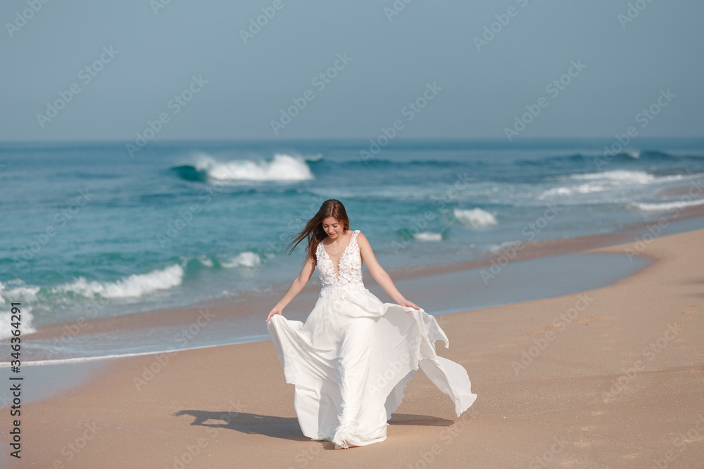 Bride walking along sea coast in the wedding dress. Bride walking along tropical sand beach  wearing beautiful wedding dress