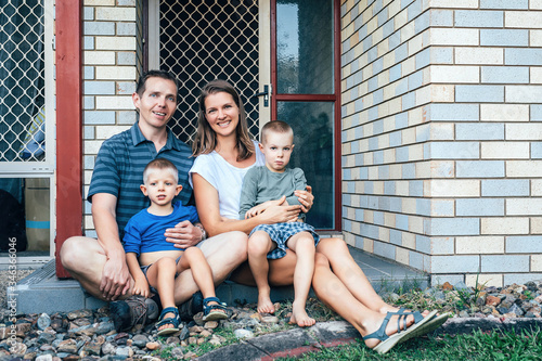 Happy family on the porch of their house. Parents with children in the summer. Mom, dad and kids.