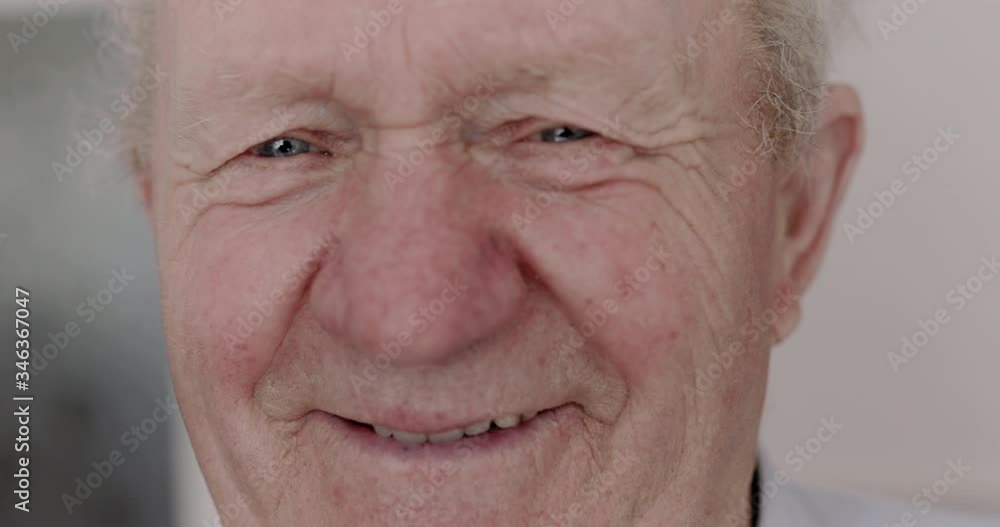 Happy, cured senior man smiling into camera and putting medical mask on ear Happy, cured senior man smiling into camera and putting medical mask on ear