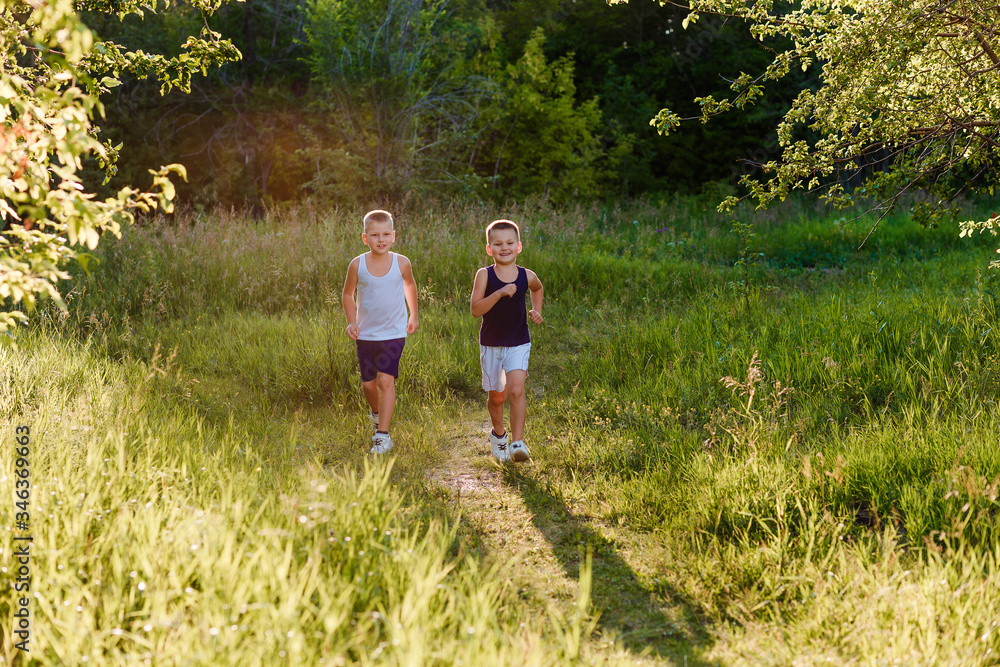 Fototapeta premium Two gay boys run through the park in the windlight in the summer