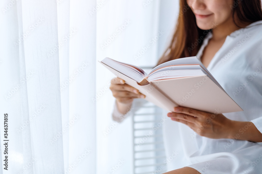 Closeup image of a beautiful asian woman reading book in a bedroom at home Closeup image of a beautiful asian woman reading book in a bedroom at home