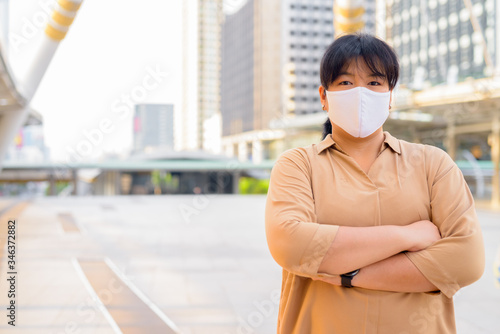 Photography Overweight Asian woman wearing mask with arms crossed at skywalk bridge