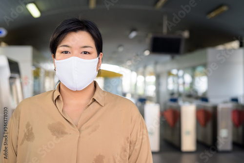 Overweight Asian woman with mask for protection from corona virus outbreak at the sky train station