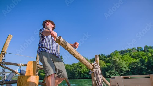 strong, happy and energetic raftsman steer the log raft with a long oar. photo