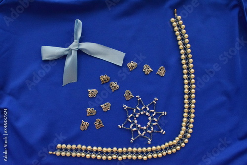 Snowflake, necklace, bow, shell, on a blue background. The view from the top.
