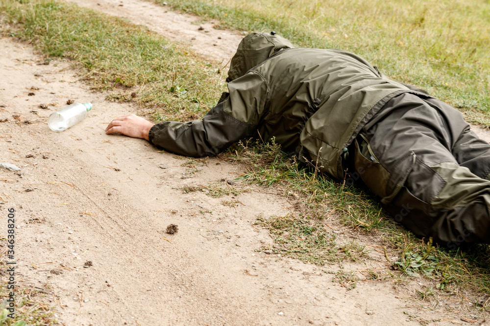 a creeping man on a field road reaches for a bottle a creeping man on a field road reaches for a bottle