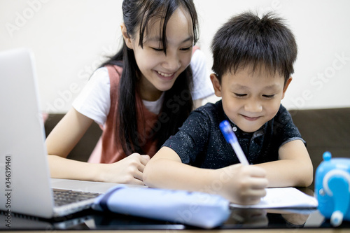 Happiness little brother studying with big sister at home,kid writing a book,smiling girl is teaching,helping and child boy learning,student doing school homework,education with happy enjoy and fun