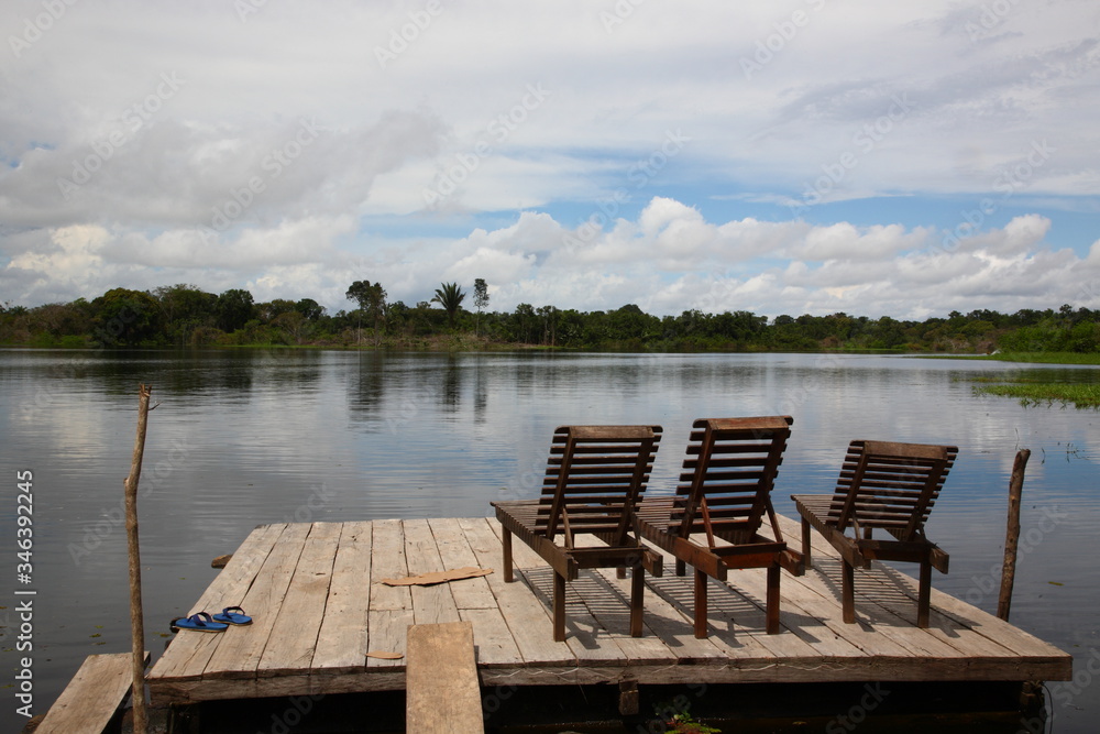 Landscape of Amazon jungle river with floating boat and lodge deck chair on water, Brazil Landscape of Amazon jungle river with floating boat and lodge deck chair on water, Brazil