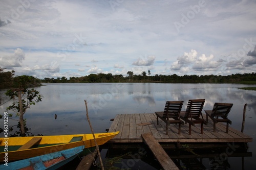 Landscape of Amazon jungle river with floating boat and lodge deck chair on water, Brazil