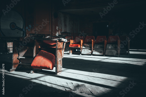Sare, zniszczone fotele w ciemnym, opuszczonym kinie w blasku promieni słonecznych photo