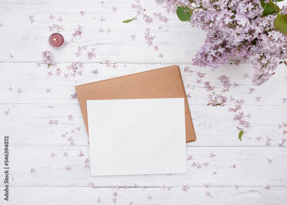 One Craft envelop, white paper on it, lilac and purple candle on old white wooden background One Craft envelop, white paper on it, lilac and purple candle on old white wooden background
