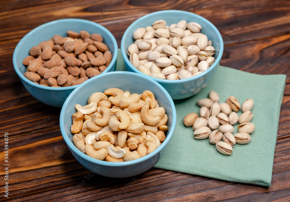 Mix of nuts on a old rustic table. Gold pistachios, cashews, almond Mix of nuts on a old rustic table. Gold pistachios, cashews, almond