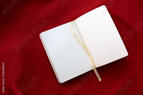Obraz na płótnie Open notebook on a red background imitating scales. Open notebook in a box on a burgundy background with place for text. w salonie