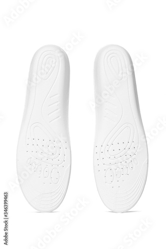 Subject shot of two white insoles with sketchy feet drawings and ventilation holes on the bottom. The orthotic insoles are isolated on the white backdrop. 