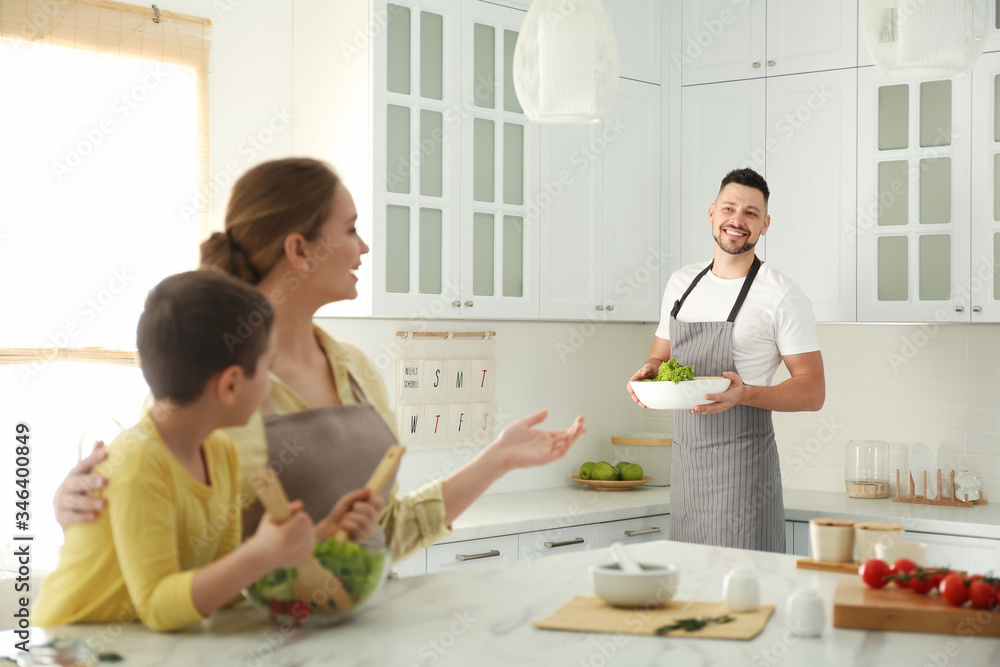 Happy family cooking salad together in kitchen Happy family cooking salad together in kitchen