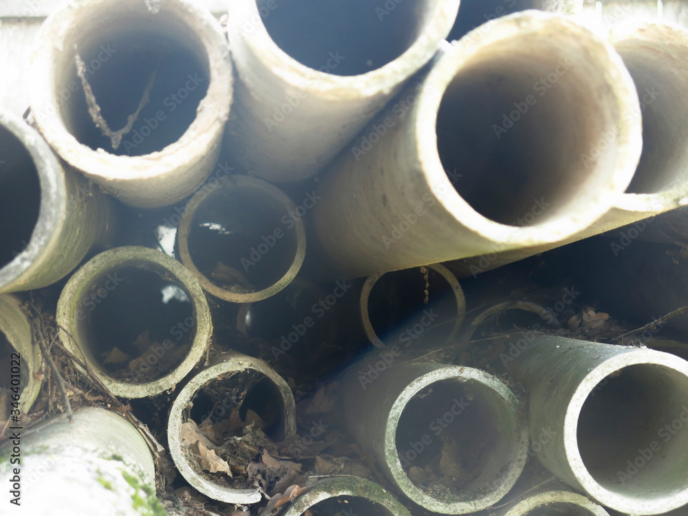 round concrete pipes are covered with moss and lie in a heap