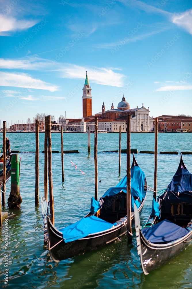 Traditional European architecture. The view of the Church of San Giorgio Maggiore with an antique bell tower near a grand canal with boats (gondolas) and the St. Marks Square in Venice, Veneto, Italy.