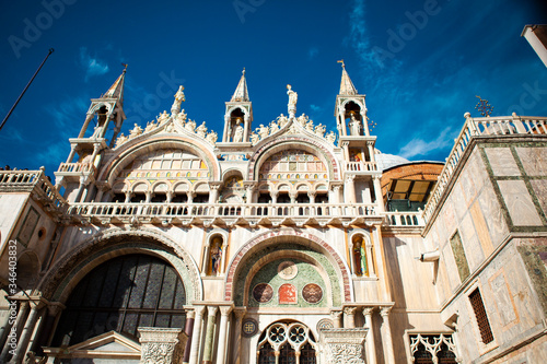 The Patriarchal Cathedral Basilica of Saint Mark is the iconic church of the Roman Catholic Archdiocese with towers, arches, lion and angel figures, golden statues & a museum in Venice, Veneto, Italy photo